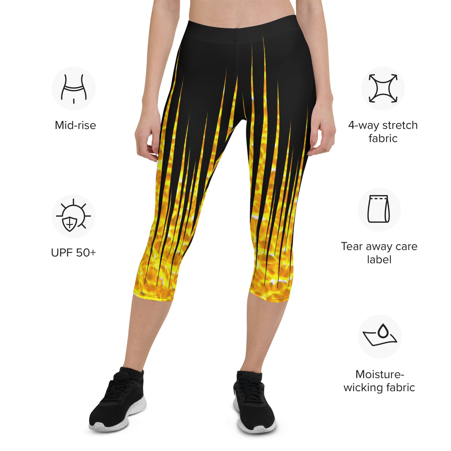 Woman modeling the Black and Fire printed Fired Up Capri leggings high-stepping from the front with feature descriptions.