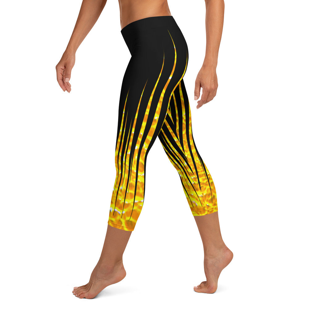 Woman modeling the Black and Fire printed Fired Up Capri leggings from the side on tiptoes.