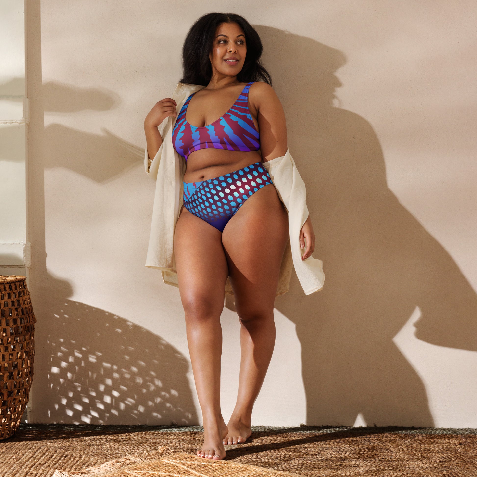 Woman modeling the Betta Ruk Bakini Swimsuit in purples, reds, and blue patterns from the front with a summer blouse.