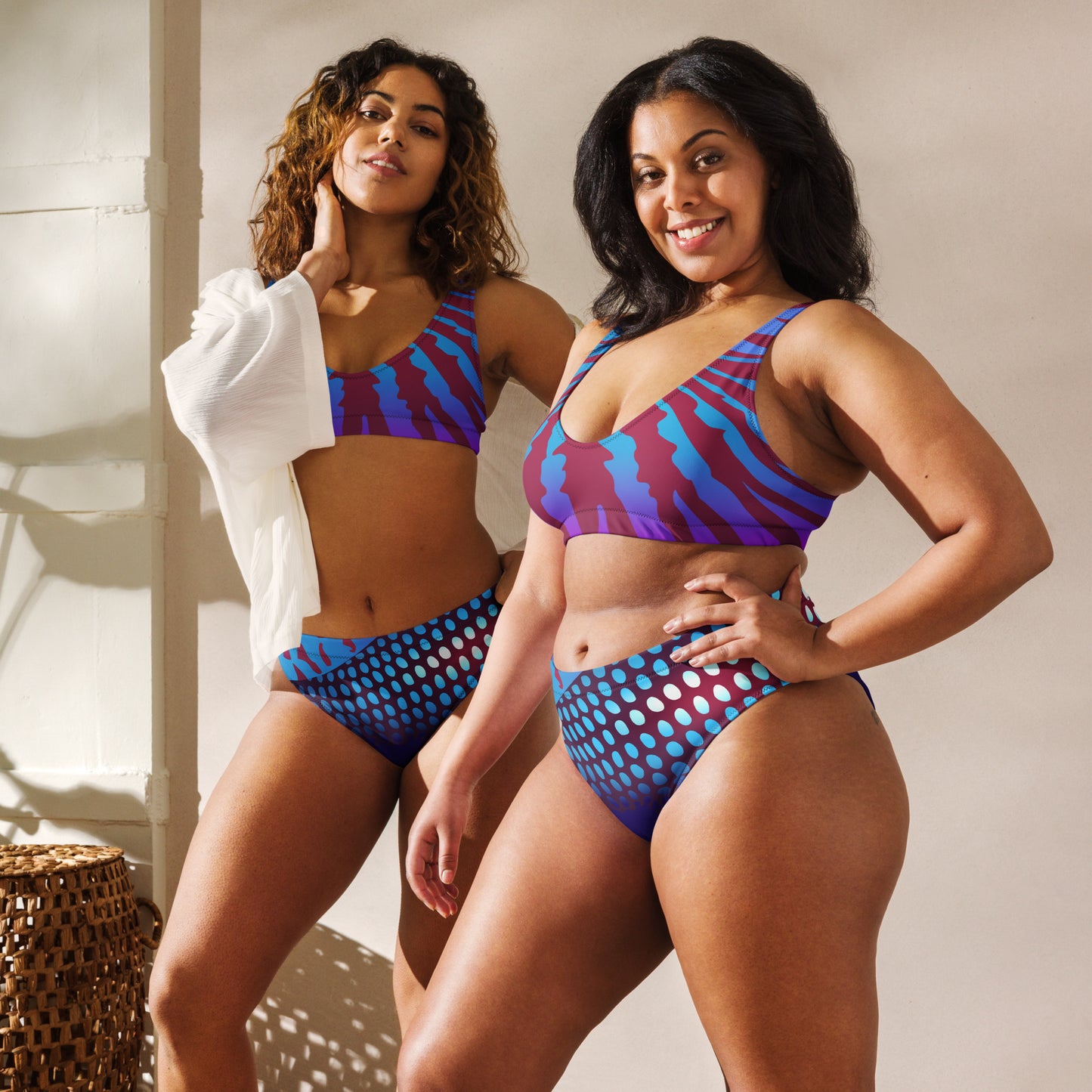 Two women modeling the Betta Ruk Bakini Swimsuit in purples, reds, and blue patterns from the front in an indoor setting.