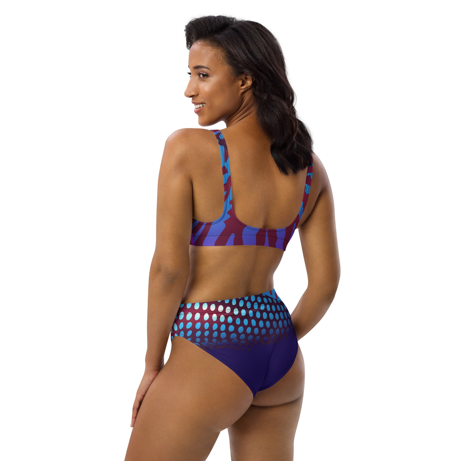 Woman modeling the Betta Ruk Bakini Swimsuit in purples, reds, and blue patterns from the left back.