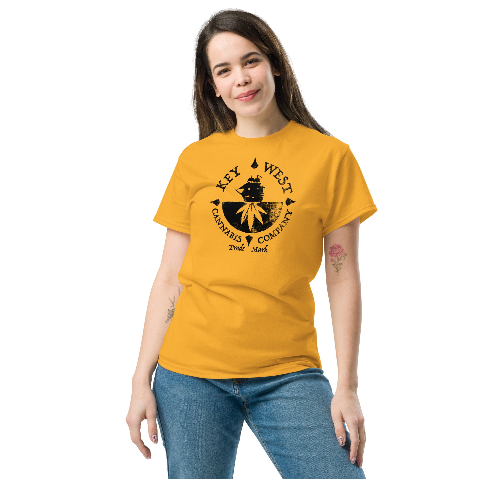 Woman modeling the Key West Cannabis Company Brand graphic in black on a Gold Color T-shirt from the front.